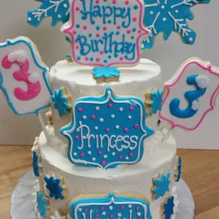 Gorgeous Frozen inspired tiered cake. Topped with deliciously hand decorated sugar cookies.