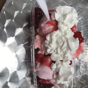 a plastic container of ice cream and strawberries
