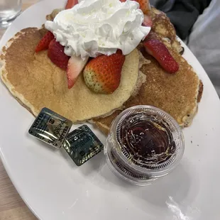 Three pancakes with strawberries and whipped cream