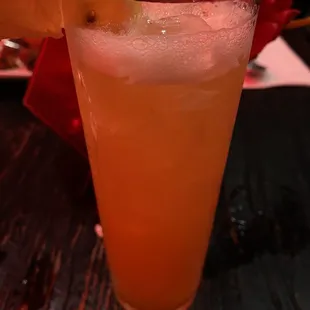 a glass of orange juice with a slice of lemon