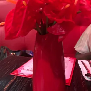 a vase of red flowers on a table