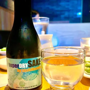 a bottle of superdry sake next to a glass of water