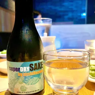 a bottle of superdry sake next to a glass of water