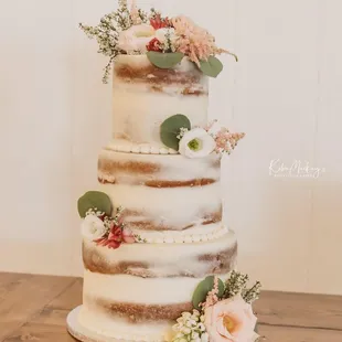 a three tiered wedding cake with fresh flowers