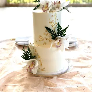 Two tiered wedding cake with gold leaf specks and orchids