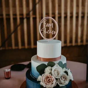 a three tiered cake with white and pink flowers