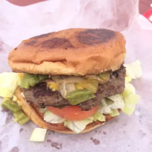 Sugar's Burger - green chile cheeseburger, bacon, mushrooms, mayo, grilled onion, lettuce and tomato on a grilled bun.