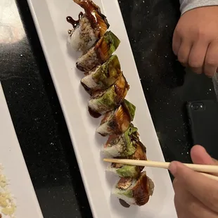 a person holding chopsticks over a plate of sushi