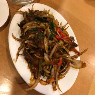 a plate of stir fried beef with onions and peppers