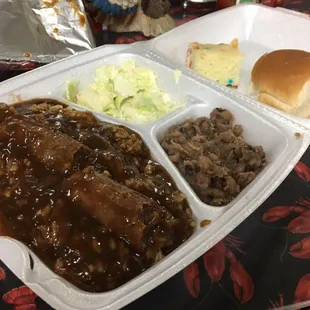 Plate lunch of fresh homemade sausage and gravy over rice, black-eyed peas, cole slaw, roll, and cake