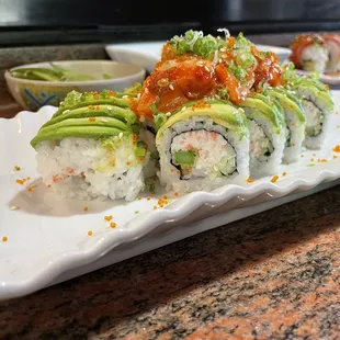 a plate of sushi with avocado and sauce