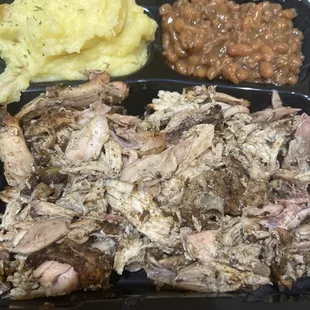 a tray of pulled pork, mashed potatoes, and beans
