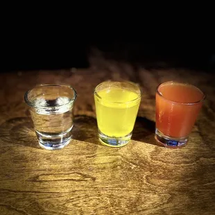 three glasses of juice on a wooden table