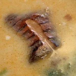 a piece of meat in a bowl of soup