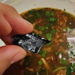 Spicy beef soup, with a piece of plastic inside it .