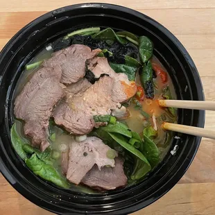 a bowl of soup with chopsticks