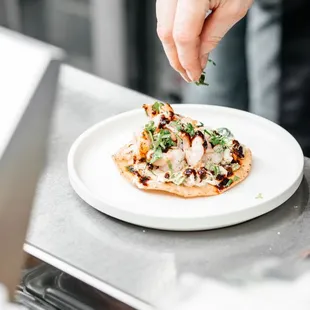 a person putting herbs on a pizza