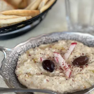 a bowl of dip with olives and pita chips