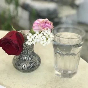 a glass of water and a vase of flowers