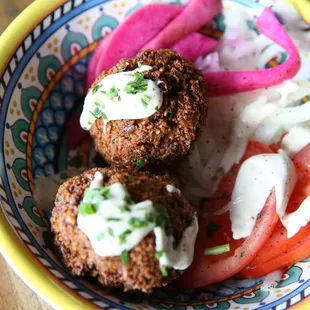 VEGAN FALAFEL IN PAIRS: 2 falafel pieces served with onion, pickled turnips, and tomato.