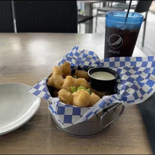 a basket of fried shrimp with a side of dipping sauce