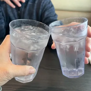 two people holding glasses of water