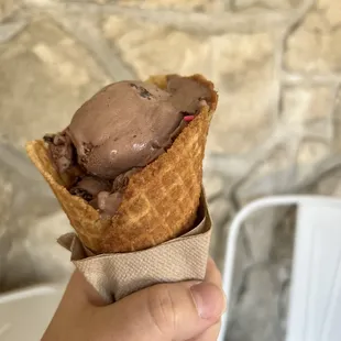 a hand holding a cone of ice cream