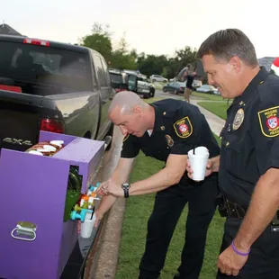 two police officers placing candy into a purple box