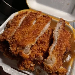 two pieces of fried chicken in a styrofoam container