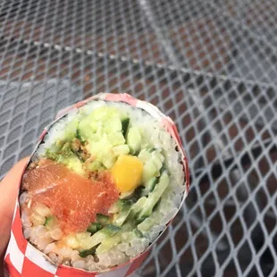 a hand holding a roll of sushi