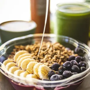 a bowl of granola, bananas, blueberries, and yogurt