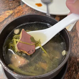 a person holding a spoon over a bowl of soup