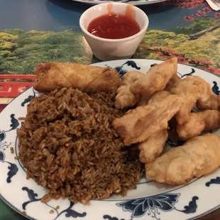 Sweet and sour chicken with fried rice and an egg roll.