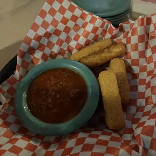 a bowl of chili sauce and some breadsticks