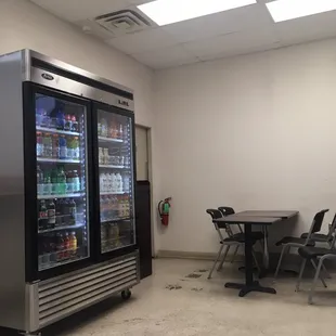 a room with a table, chairs, and a refrigerator