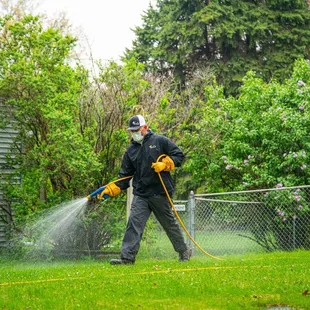 a man spraying a lawn with a hose