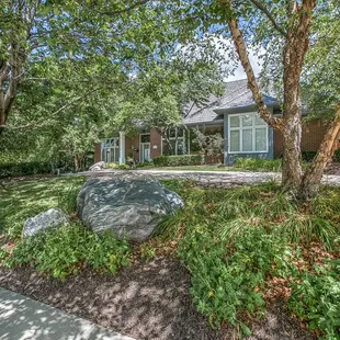 the front of a home with a large rock in the front yard