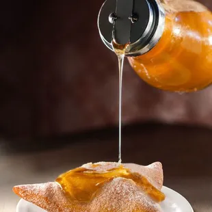 a person pouring syrup onto a plate of food