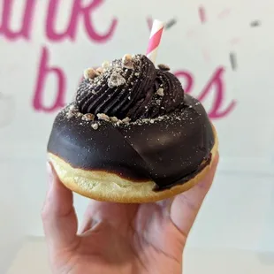 a hand holding a chocolate frosted donut