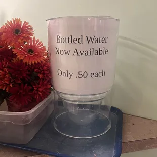 a cup of bottled water on a tray with flowers