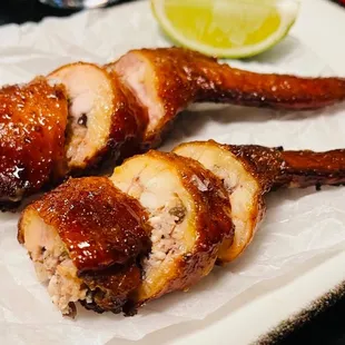 two pieces of chicken wrapped in bacon and garnished with a slice of lime