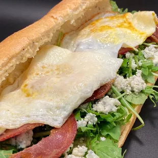 an egg and bacon sandwich with lettuce