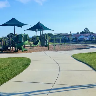 Walkway to the play structures, located after the tables/benches area. Seating around the perimeter. Nice park to bike and scooter around!