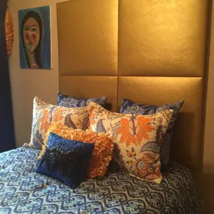 Contemporary large head board exaggerates the height and size of this small bedroom, layered pillows make the bed look large as well.