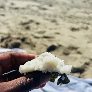 a person holding a piece of food on the beach