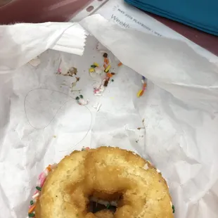 a hand holding a donut with sprinkles
