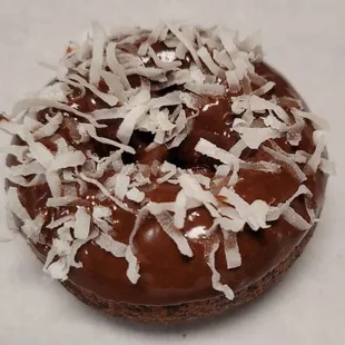 a chocolate donut covered in coconut flakes