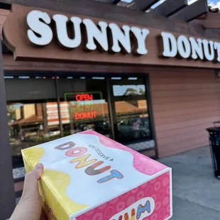 a hand holding a box of donuts