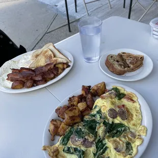 Greek horizon omelette with home fries and raisin toast, and eggs with bacon, home fries, and white toast