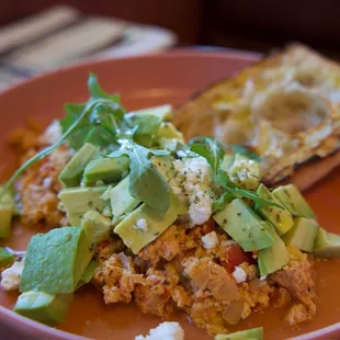 Mediterranean Eggs | Simmered Tomato, Feta, Greek Oregano, Olive Oil, Avocado, Grilled Ciabatta